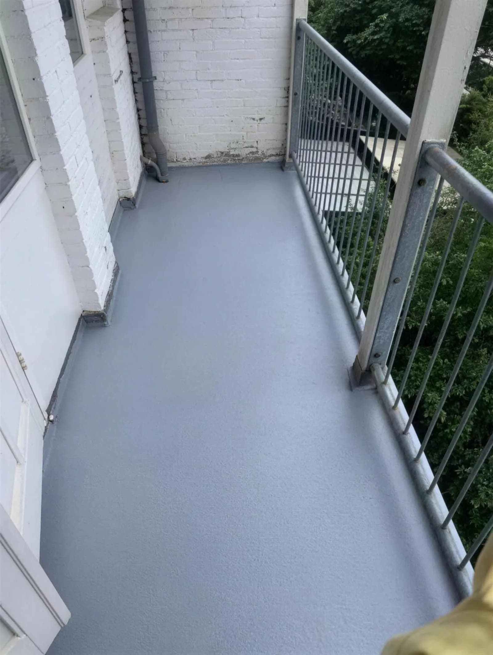 Balkon met gecoate vloer, omgeven door groen